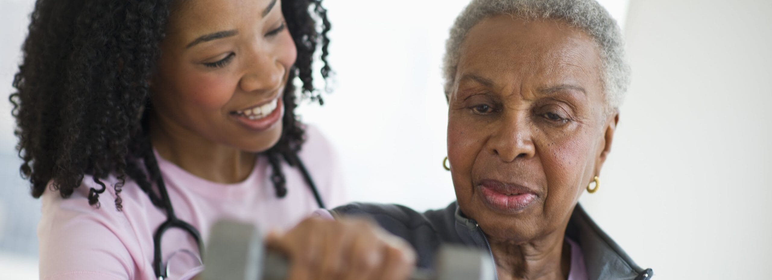 Nurse helping woman exercise with dumbbell