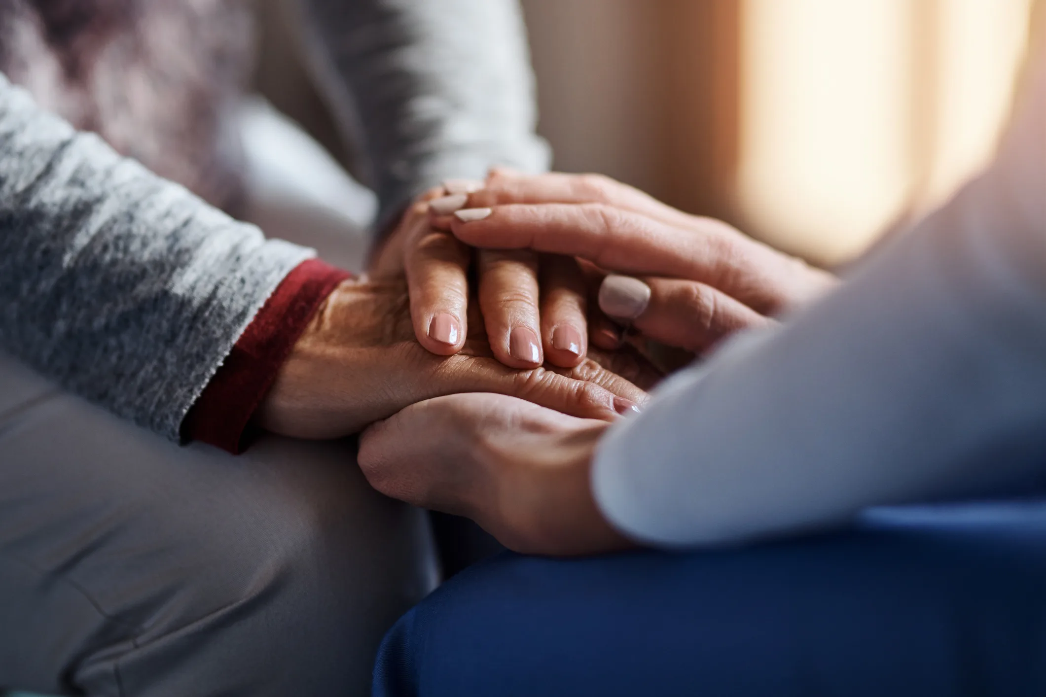 Cropped shot of a home care nurse holding a senior woman’s hands at her home