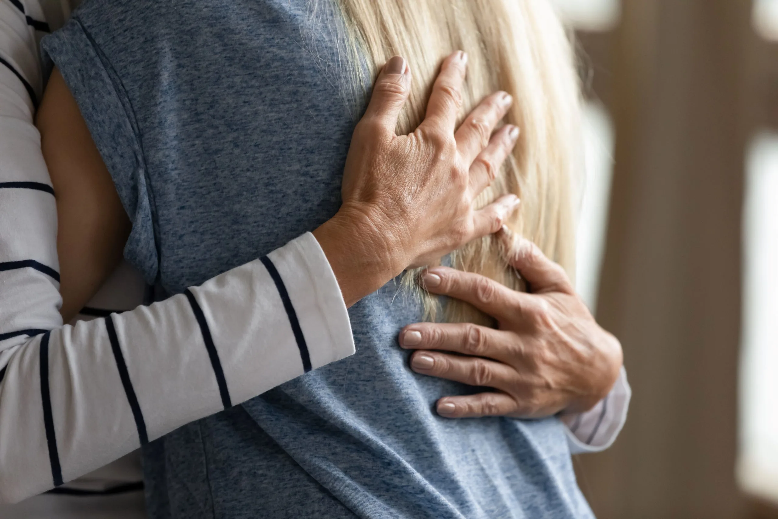 Close up shot of two people hugging, showing hands on a person's back